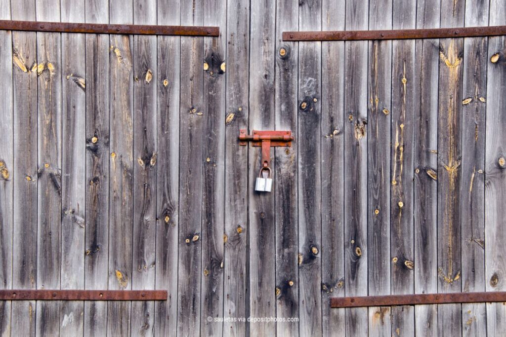 Das Bild zeigt eine Scheunentür aus Holz, die durch ein Vorhängeschloss abgeschlossen ist – als Metapher für digitale Privatsphäre (Bildquelle: sauletas via depositphotos).