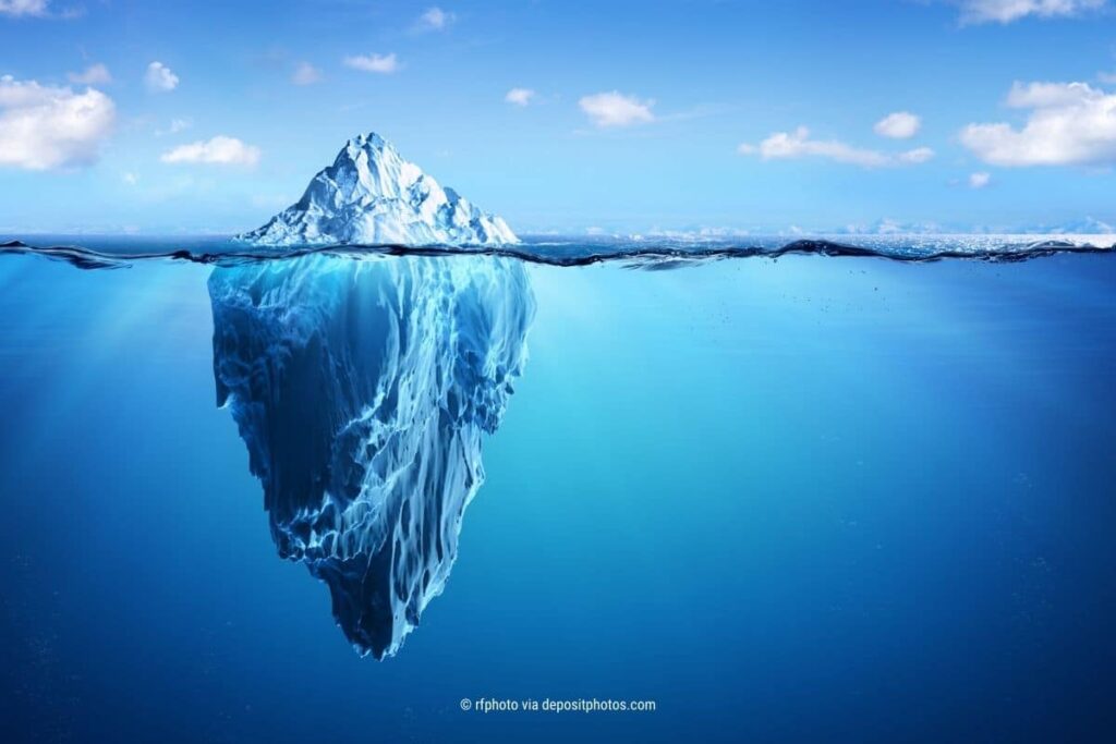 Das Bild zeigt einen Eisberg aus der Perspektive der Wasserlinie, also den sichtbaren Teil oberhalb und den unsichtbaren Teil im Wasser unterhalb. Der verrückte kumulus Jahresrückblick 2023: (Photocredit: rfphoto via depositphotos)