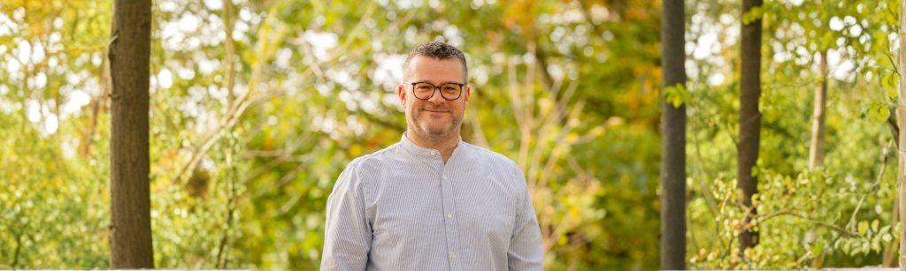 Das Bild zeigt Christoph Ziegler (Moderator, Digital Stratege, Systemischer Coach) in einer herbstlichen Landschaft (Photo: Daniel Schmitt, Spitzlicht Fotografie Wuppertal, KI-bearbeitet).